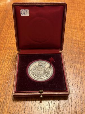 a silver coin in a red case sitting on a wooden table
