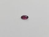 a red oval shaped ruby stone on a white surface