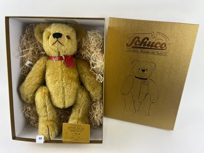un ours en peluche jaune dans une boîte, avec un nœud papillon rouge