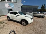 white nissan juke parked in front of a building in a parking lot