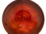 an orange glass bowl with a metal stand on a white surface
