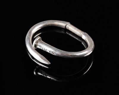 un gros plan d'une bague en argent munie d'un crochet, posée sur une surface noire