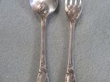 two silver spoons and a fork on a table