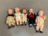 several antique dolls are lined up in a row on a gray surface