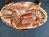 brown leather purse sitting on a black surface with a black background
