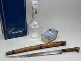 a glass bottle, a knife, and a box of matches on a table