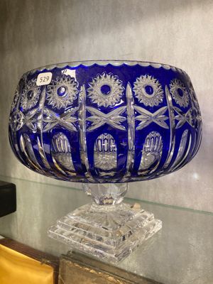 un grand saladier en verre bleu posé sur une table en verre