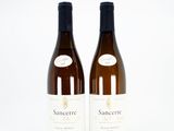 two bottles of white wine sitting next to each other on a white surface