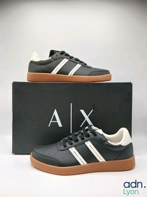 une paire de baskets Adidas noires et blanches dans une boîte