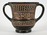 a black and brown vase with a design on it