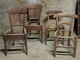 trois chaises en bois placées les unes à côté des autres devant un mur en pierre