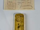 un vieux lingot d'or posé sur une table, à côté d'un ticket de caisse