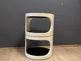 a white trash can sitting on the floor next to a gray wall