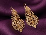 une paire de boucles d'oreilles en or posées sur un tissu violet