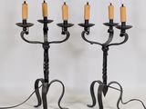 une paire de chandeliers en fer noir, chacun orné d'une bougie