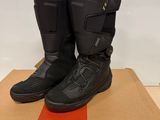 des bottes de moto noires posées sur une boîte en carton posée sur une table