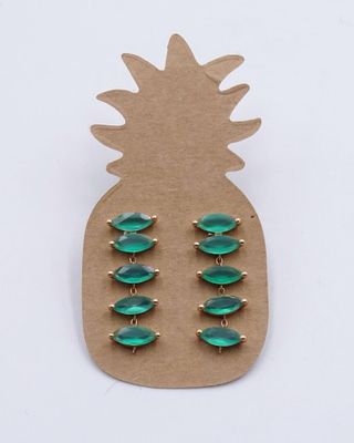 un gros plan sur une paire de boucles d'oreilles vertes posées sur un carton