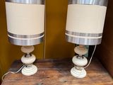 two lamps on a wooden table with a brown wall in the background
