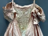 a pink dress hanging on a hanger on a blue wall