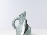 vase en céramique gris et blanc posé sur une surface blanche, sur fond blanc