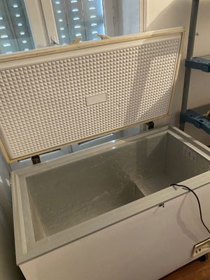 a white chest freezer sitting on the floor next to a ladder