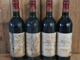 quatre bouteilles de vin sont alignées sur une étagère en bois
