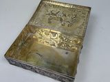 an old silver box with a design on it on a white surface