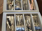 a lot of silverware in the trays on the table