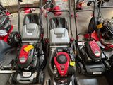Plusieurs tondeuses à gazon sont alignées dans un garage
