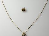 a gold necklace and earring set with a bee on it