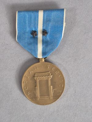 une vieille médaille ornée d'un ruban bleu et blanc sur un fond gris