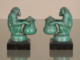 pair of green monkey figurines sitting on a glass table