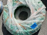 un sac de fil de fer et un rouleau de fil de fer posés par terre