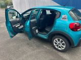 la portière ouverte d'une petite voiture bleue garée sur un parking