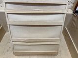 a white chest of drawers in the corner of a room