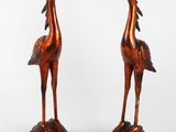 paire de sculptures de couleur bronze représentant deux oiseaux, posées sur un socle en bois