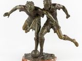 an image of a bronze statue of two men playing soccer