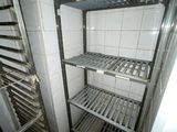 a metal rack in the corner of a white tiled room