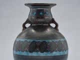 a blue and black vase sitting on a white surface