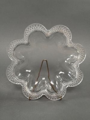 plat en verre transparent en forme de fleur, muni d'une poignée dorée sur fond gris