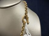 a gold necklace with a white tag on it on a mannequin