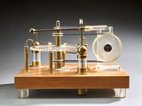 une petite maquette de machine à vapeur posée sur un socle en bois