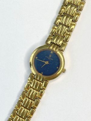 une image représentant une montre en or avec un cadran bleu sur un fond blanc
