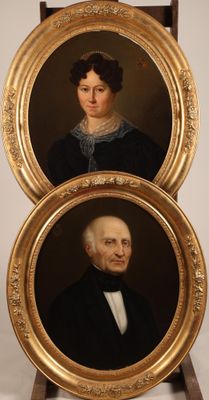 two framed portraits of a man and a woman in formal clothing