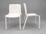 pair of white plastic chairs against a gray background