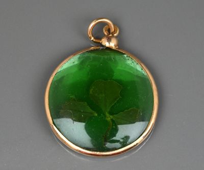 un gros plan d'un pendentif en verre vert contenant une feuille