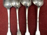 four spoons are lined up in a row on a red surface