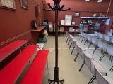 Des tables et des bancs sont alignés dans une pièce recouverte d'un tapis rouge