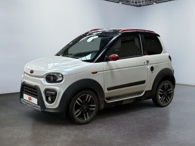 La petite voiture blanche est garée dans une grande pièce blanche.
