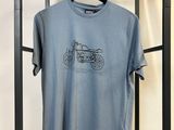 un t-shirt bleu orné d'une moto, suspendu à un portant